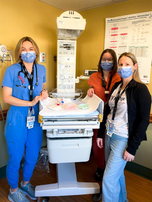 Two nurses in front of newborn weigh station